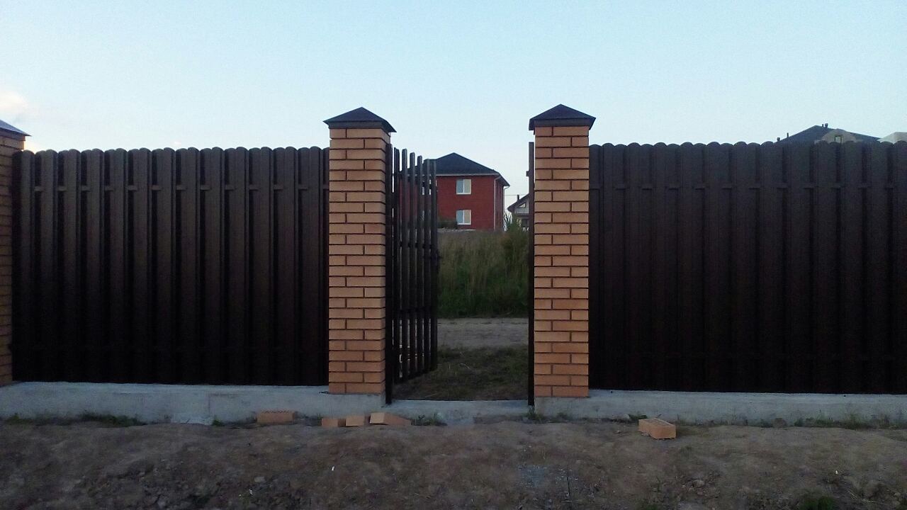 Забор из профнастила с кирпичными столбами на ленточном фундаменте фото